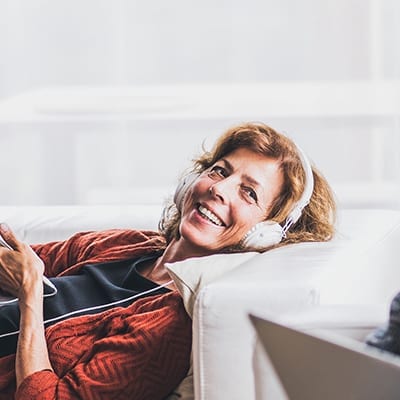 Happy Senior Couple With Tablet And Smartphone Relaxing At Home.
